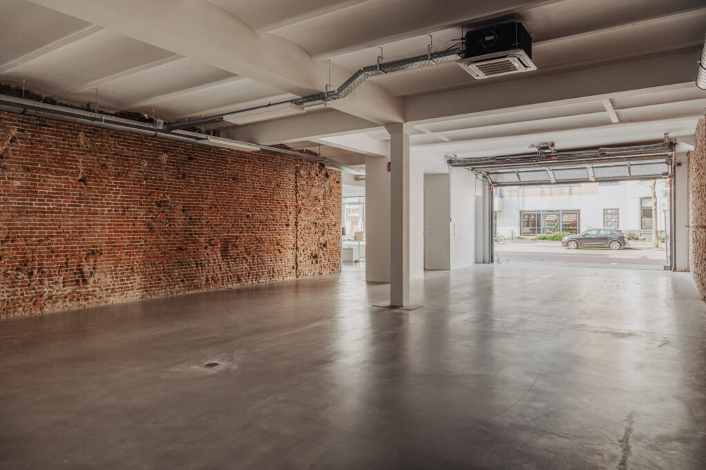 Lege industriële ruimte met betonnen vloer, bakstenen muur en open garagepoort aan de Plantage Middenlaan.